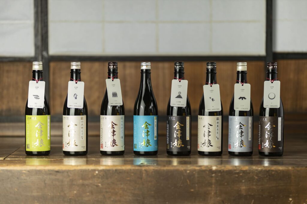 The 'Aizumusume Minori' series, based on the 'Ichiden-Ichijo' concept of 'one brew per rice field.' Each bottle is named after the address of its rice field. From left: 'Tokuhisa 114,' 'Haguro-Nishi 64,' 'Haguromae 27,' 'Nakakari,' 'Hanasaka-Sakai 22,' 'Haguro 46,' 'Haguro 7,' and 'Matsubara 8.'