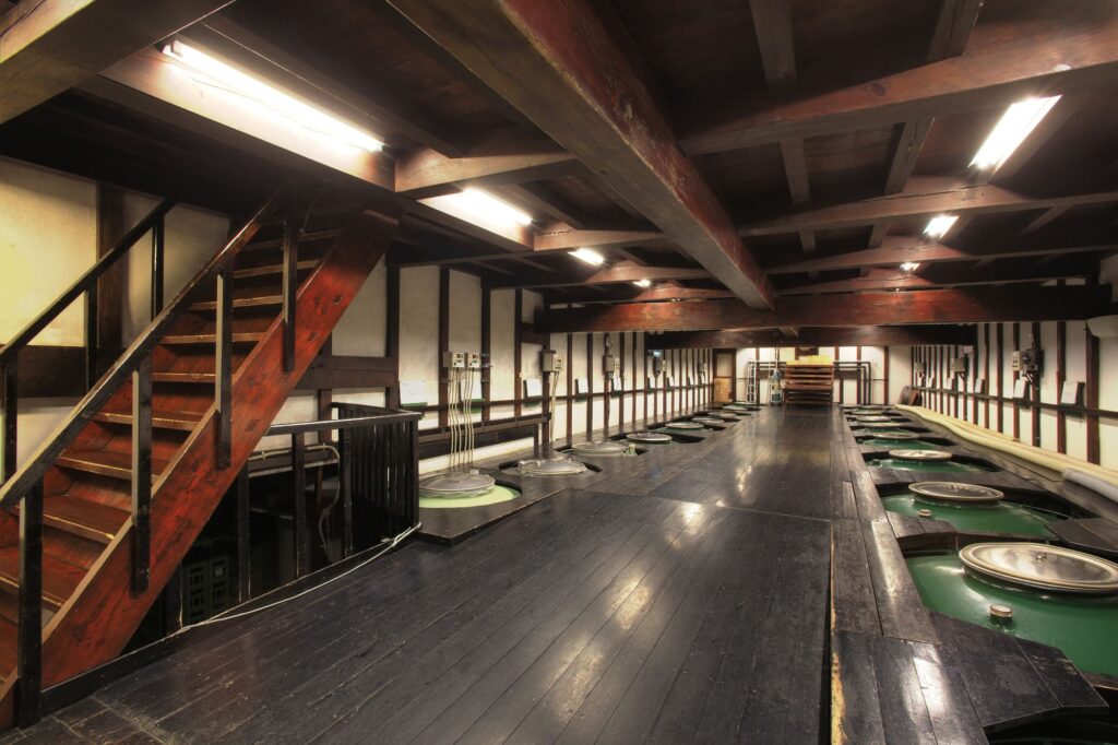 The floor and walls of the brewing house, which was relocated from Kitakata City, are covered in steel plates polished to a shine. The enamel tanks seen throughout will be replaced in the future with wooden vats made from locally sourced cedar.